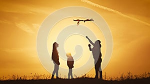 Happy family playing with a kite while on meadow, sunset, in summer day. Funny family time. Happy little girl launch a