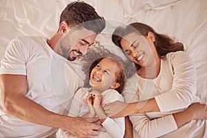 Happy family playing and laughing together on the bed having fun at home on a weekend. Playful and carefree parents