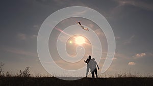 Happy family playing outdoors, flying kite flying. Silhouette of children with a kite at sunset. Team work, team play