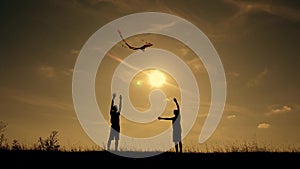 Happy family playing outdoors, flying kite flying. Silhouette of children with a kite at sunset. Team work, team play