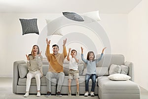 Happy family playing with pillows in room