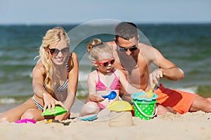 Happy family playing with sand toys on beach