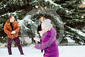 Happy family playing snowballs in winter park