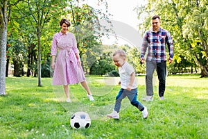 Happy family playing soccer at summer park