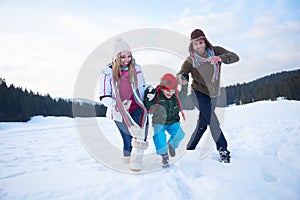 Happy family playing together in snow at winter
