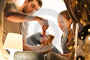 Happy family playing with toy in kids tent at home