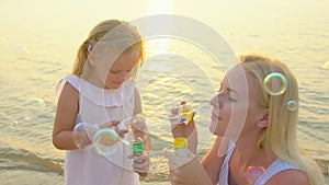 Happy family Playing wit Soap Bubbles outdoor on the beach during beautiful sunset happy vacation time in slow motion