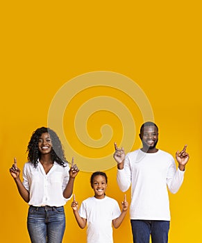 Happy family pointing upwards at copy space and looking at camera