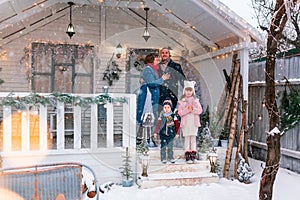 Happy family on the porch of the Christmas decorated house outdoor