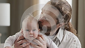 Happy family. Portrait of bearded caucasian loving father and newborn baby girl boy looking at camera dad kissing child