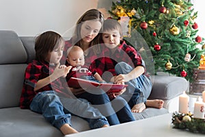 Happy family portrait on Christmas, mother, reading a book to her three children