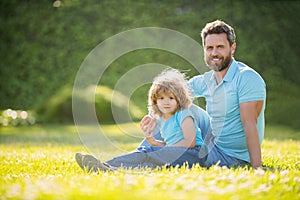 happy family portrait of father and son boy relax in summer park green grass, family love