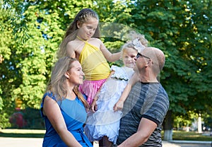 Happy family portrait on outdoor, group of four people posing in city park, summer season, child and parent