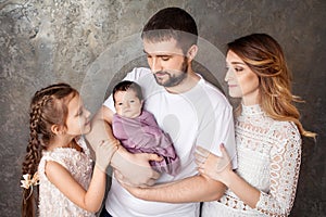 Happy family portrait.  Smiling parents with two children. Mother and father with newborn baby and toddler girl. Concept of  happy