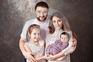 Happy family portrait.  Smiling parents with two children. Mother and father with newborn baby and toddler girl. Concept of  happy