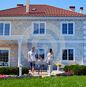 Happy family posing in front of new modern house