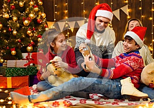 Happy family posing in new year or christmas decoration. Children and parents. Holiday lights and gifts, Christmas tree decorated