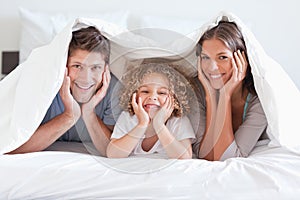 Happy family posing under a duvet