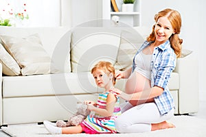 Happy family pregnant mother combing hair of little daughter