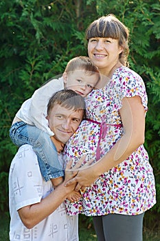 Happy family. Pregnant mother with her husband and son in the park