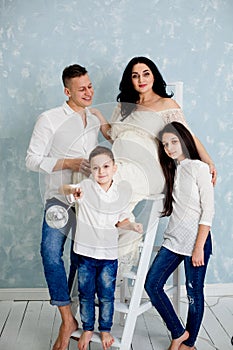 Happy family with pregnant woman and children posing in the studio