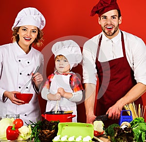 Happy family preparing healthy food in kitchen at home. Mother and father teach little son cooking.