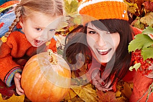 Happy family with pumpkin on autumn leaves.