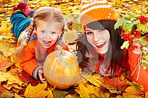 Happy family with pumpkin on autumn leaves.