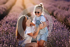 Happy family in purple lavender field. young beautiful mother and child Girl enjoy walking blooming meadow on summer day