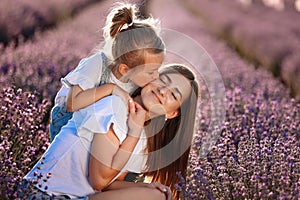 Happy family in purple lavender field. young beautiful mother and child Girl enjoy walking blooming meadow on summer day