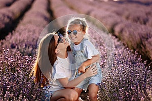 Happy family in purple lavender field. young beautiful mother and child Girl enjoy walking blooming meadow on summer day