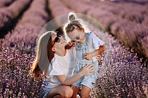 Happy family in purple lavender field. young beautiful mother and child Girl enjoy walking blooming meadow on summer day