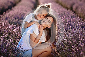 Happy family in purple lavender field. young beautiful mother and child Girl enjoy walking blooming meadow on summer day