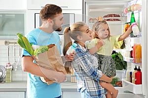 Happy family putting products into refrigerator