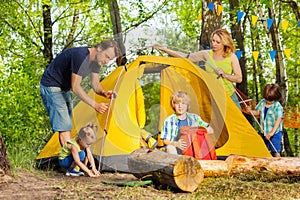 Happy family putting up a tent together in woods