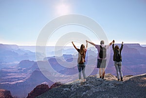 Happy family with raised hands enjoying time together on top of the mountain.