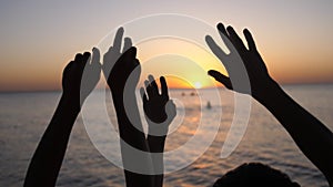 Happy family raising hands up. Hands up in the air silhouette over sunset sky.