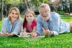 Happy family read books together in park garden.