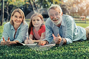 Happy family read books together in park garden.