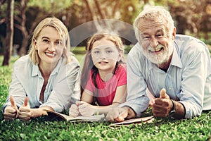 Happy family read books together in park garden.