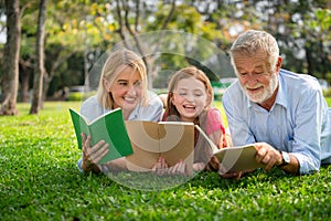 Happy family read books together in park garden.