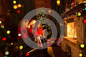 Happy family reading book at home by fireplace in warm and cozy living room on winter day christmastime