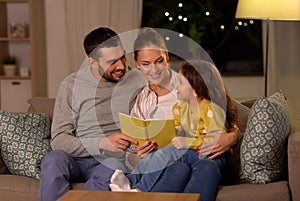 Happy family reading book at home at night