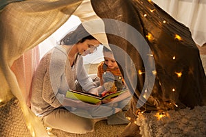 Happy family reading book in kids tent at home