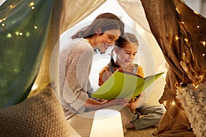 Happy family reading book in kids tent at home