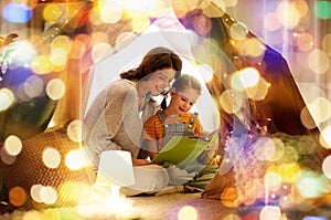 Happy family reading book in kids tent at home