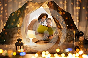 Happy family reading book in kids tent at home