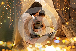 Happy family reading book in kids tent at home