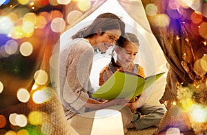 Happy family reading book in kids tent at home