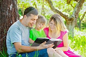 Happy family reading a book on the nature of the Bible